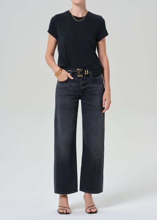 Person wearing a black t-shirt and black jeans on a grey background