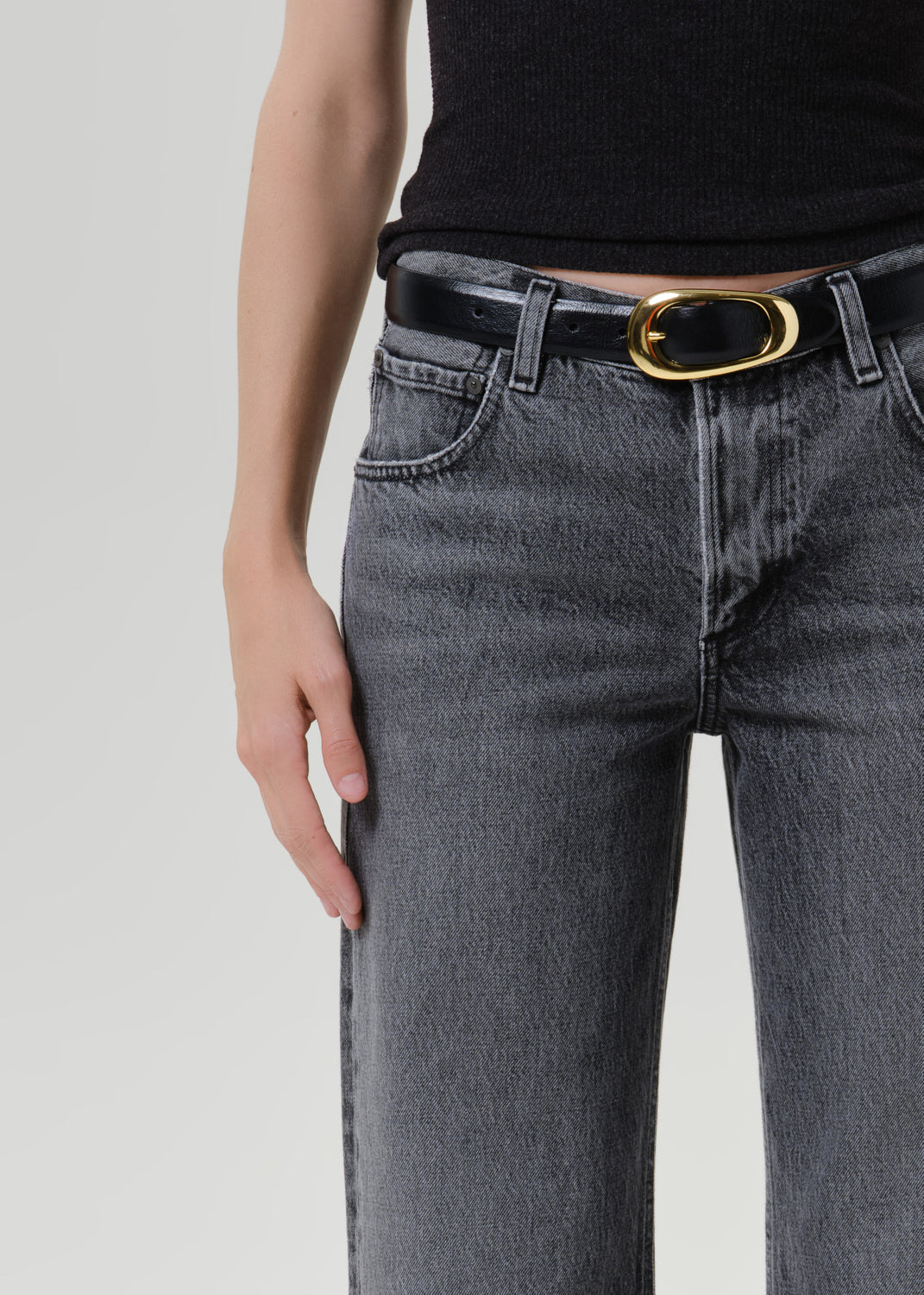 Close up of grey denim jeans with a black belt on a grey background