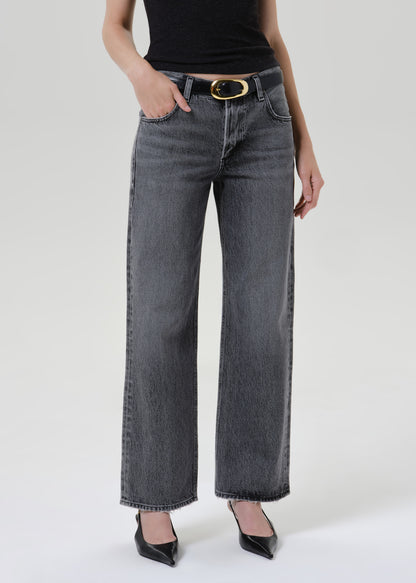 Close up of grey denim jeans with a black belt and heels on a grey background