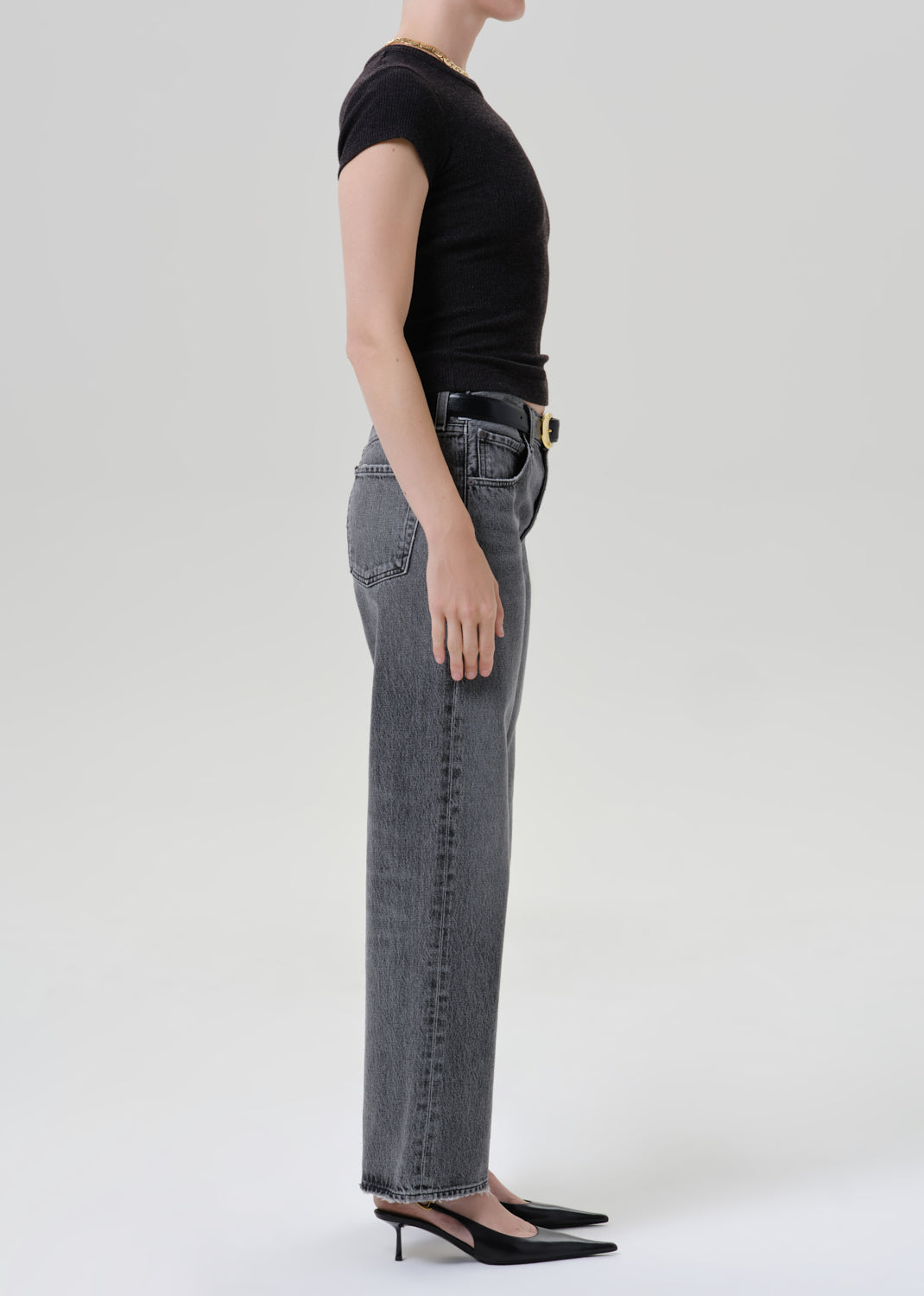 Person wearing black t-shirt with grey denim pants on a grey background
