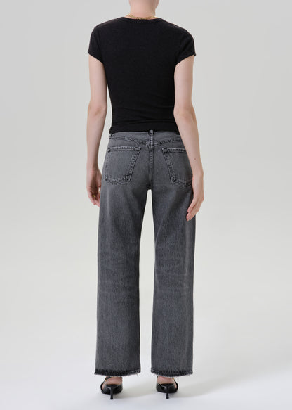 Person wearing black t-shirt with grey denim pants on a grey background