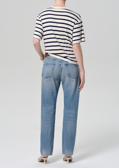 Person wearing a striped shirt and blue jeans on a white background