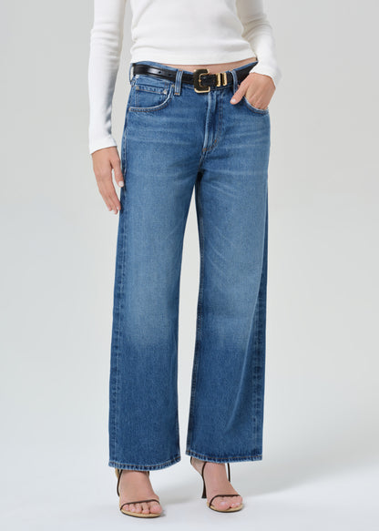 Person wearing a white top and blue jeans on a plain background