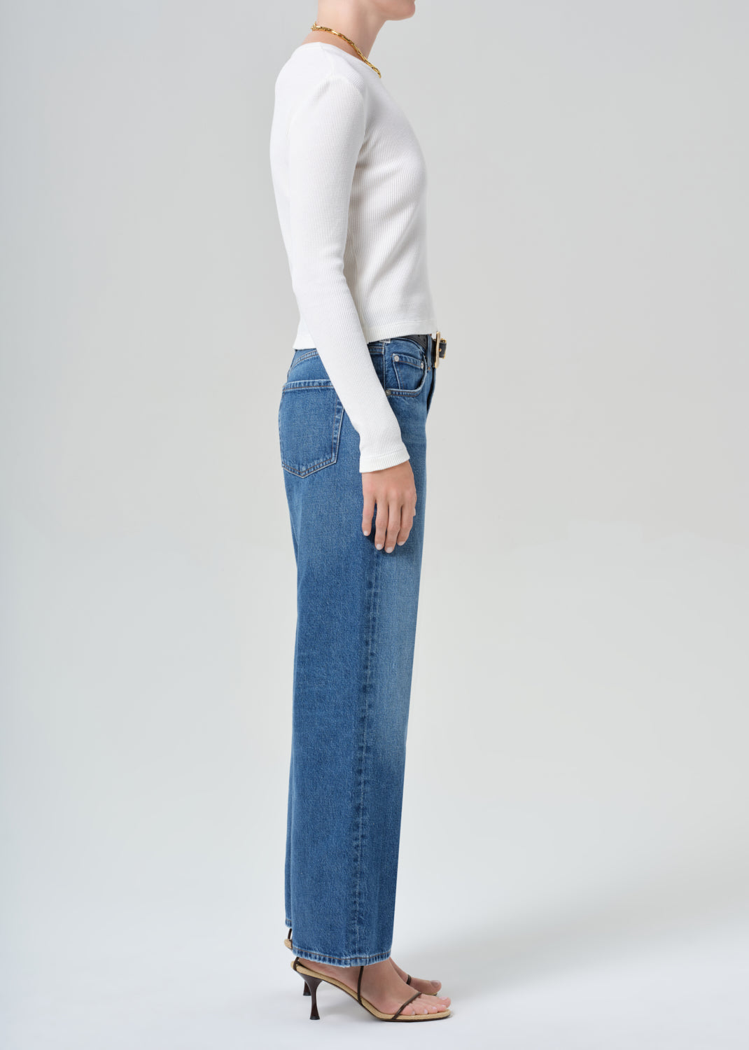 Person wearing a white top and blue jeans on a plain background