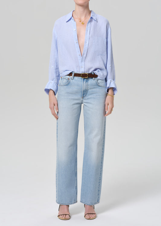 Person wearing a light blue shirt and jeans on a grey background