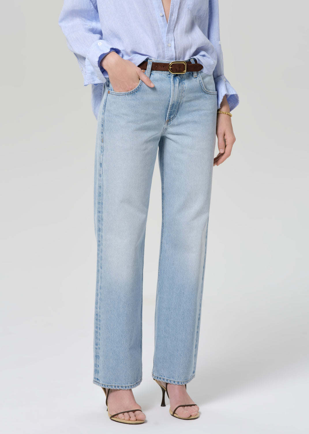 Person wearing a light blue shirt and jeans on a grey background
