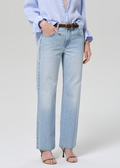 Person wearing a light blue shirt and jeans on a grey background