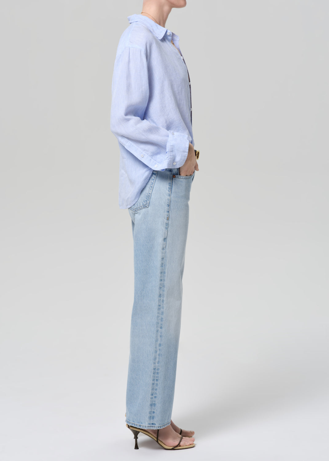 Person wearing a light blue shirt and jeans on a grey background