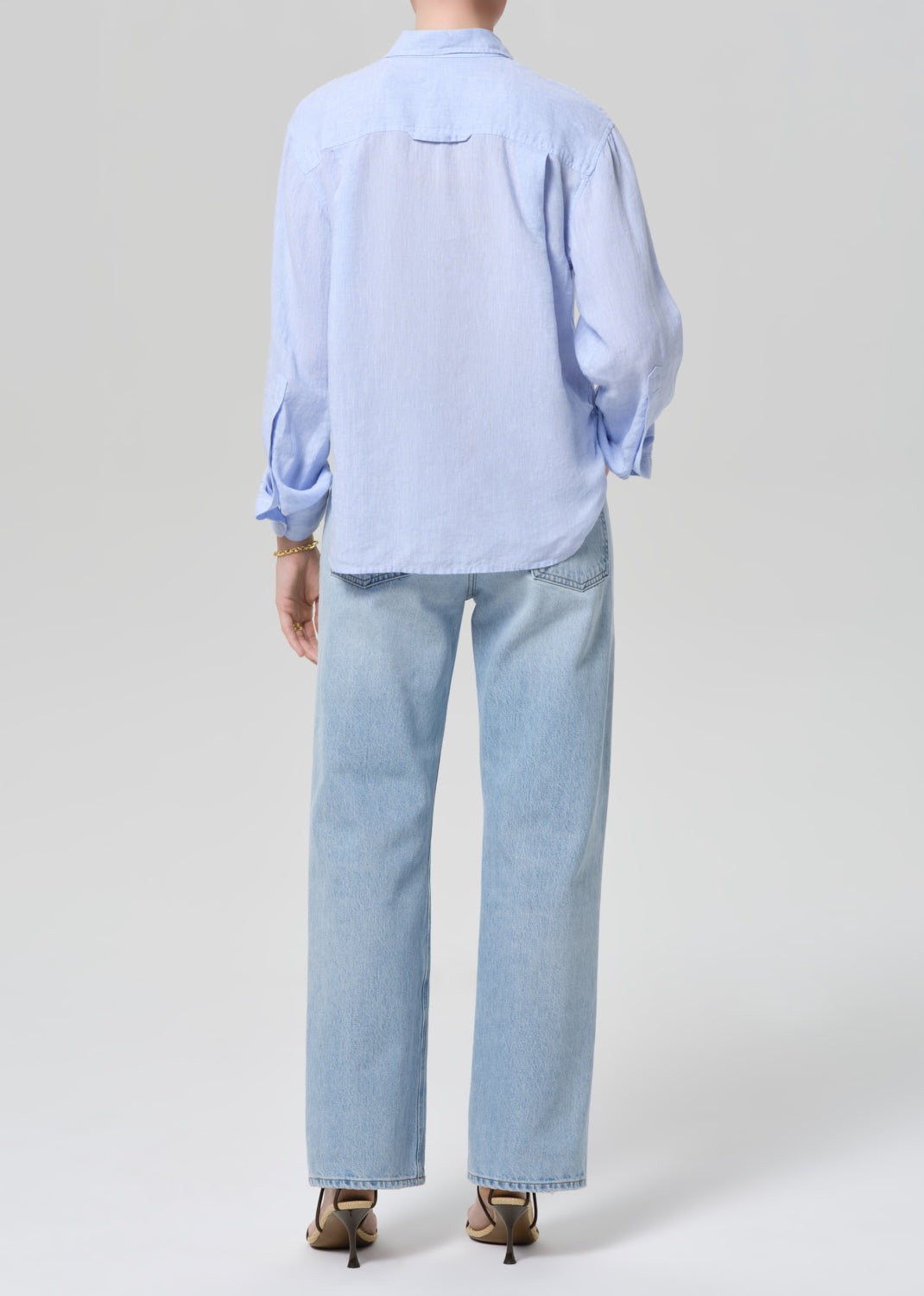 Person wearing a light blue shirt and jeans on a grey background