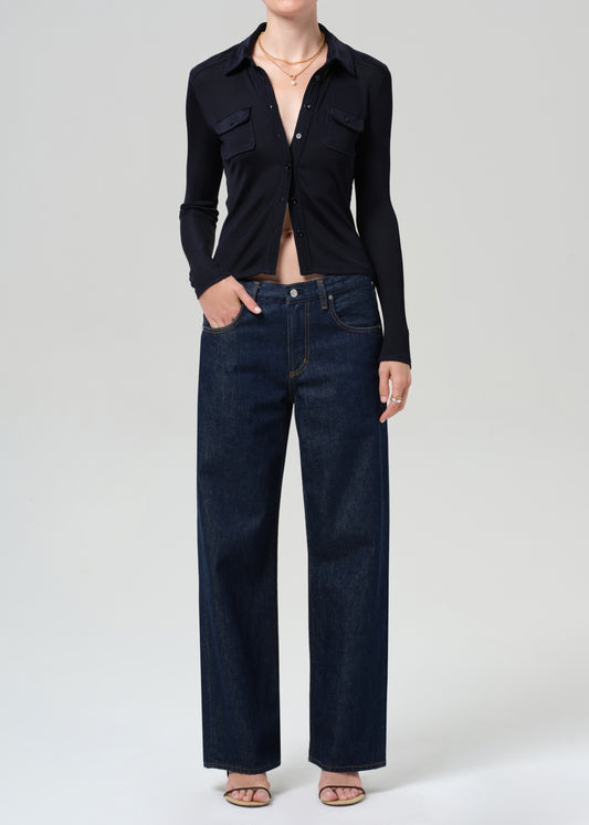 Person wearing a navy shirt and dark blue jeans on a grey background