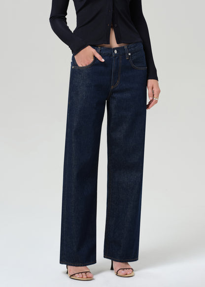 Person wearing a navy shirt and dark blue jeans on a grey background