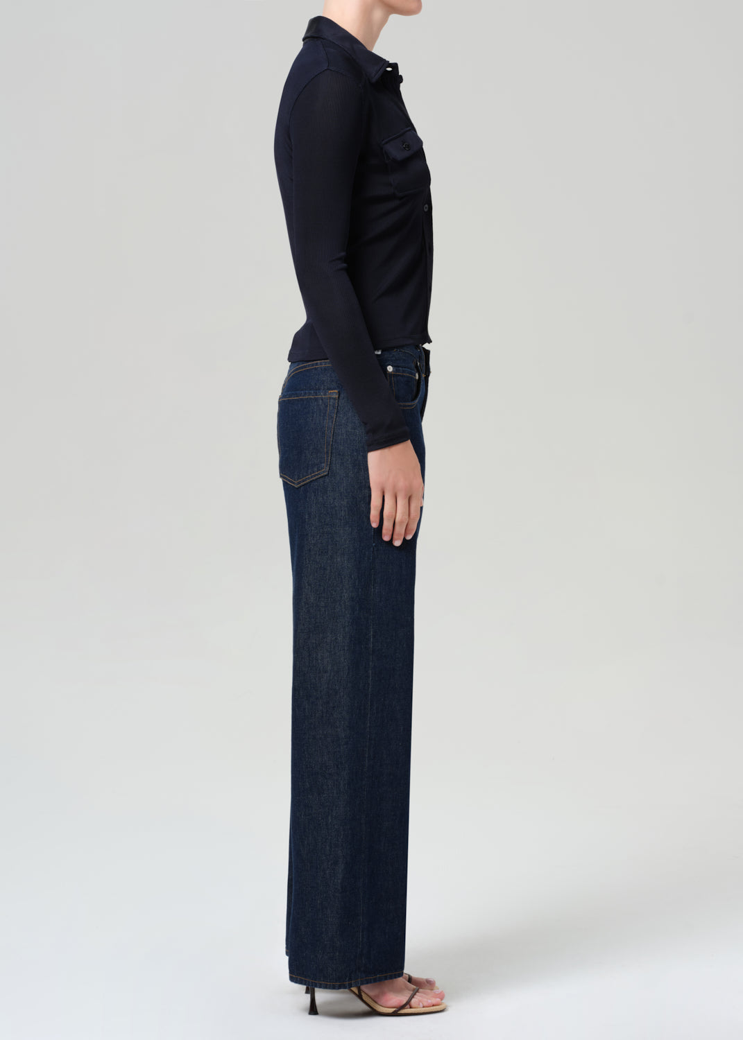 Person wearing a navy shirt and dark blue jeans on a grey background