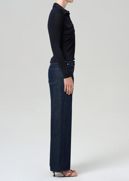 Person wearing a navy shirt and dark blue jeans on a grey background