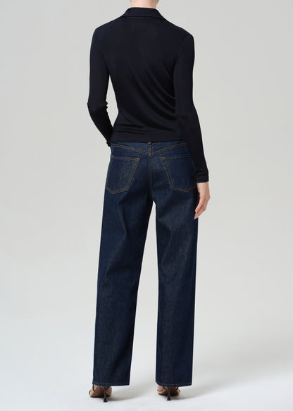 Person wearing a navy shirt and dark blue jeans on a grey background