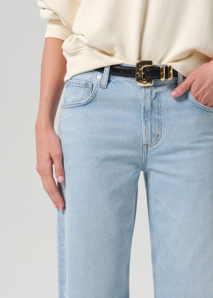 Close up shot of person wearing blue pants and black belt on a grey background