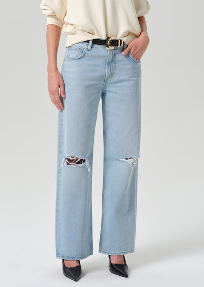 Person wearing blue pants and black heels on a grey background