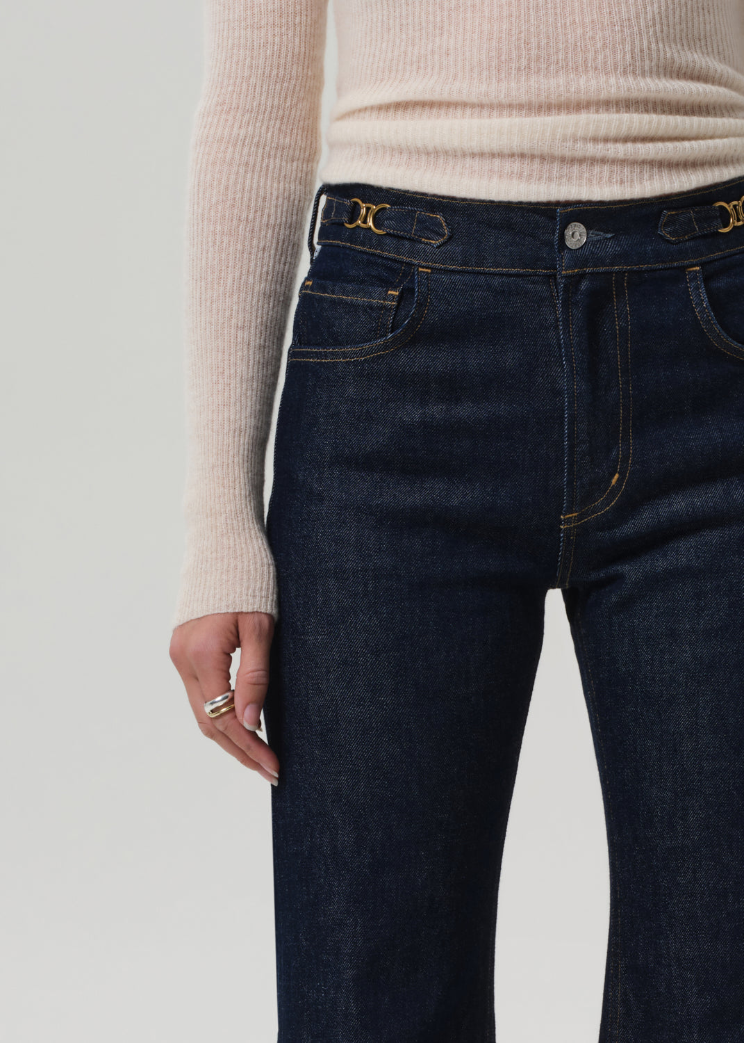 Dark blue jeans with gold hardware on a plain background