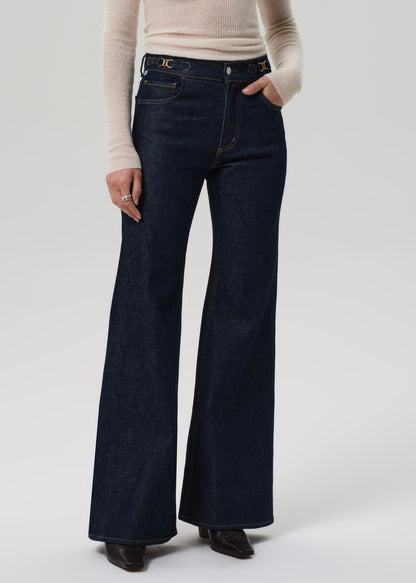 Person wearing dark blue flared jeans on a white background