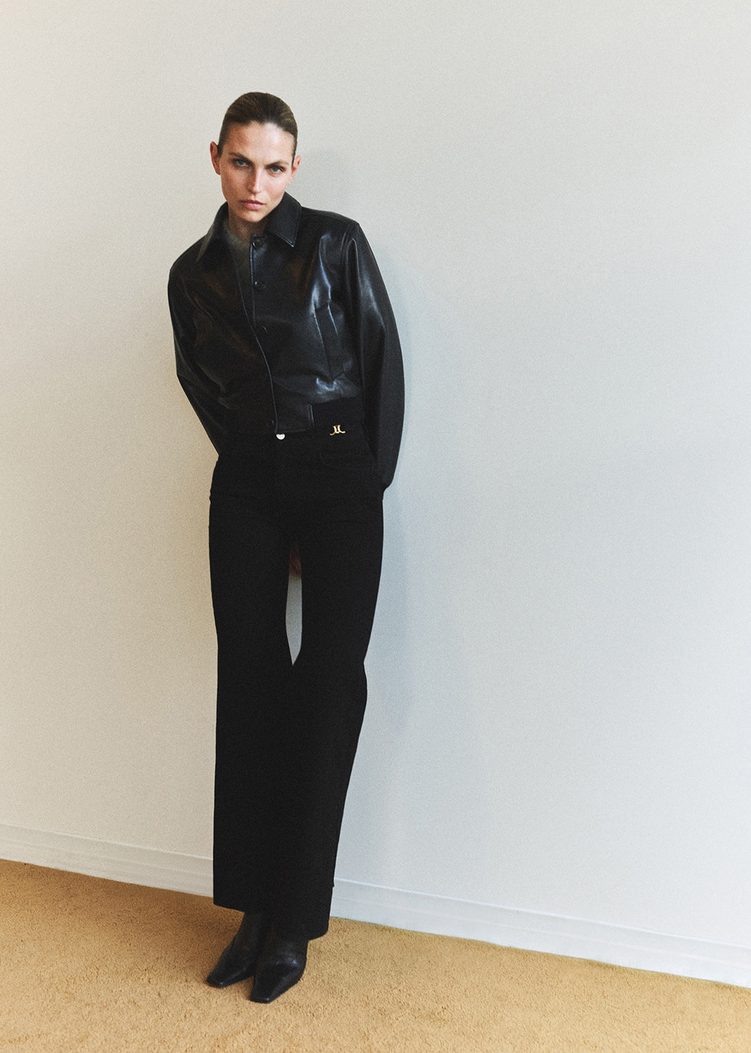 Person wearing a black outfit against a plain white wall