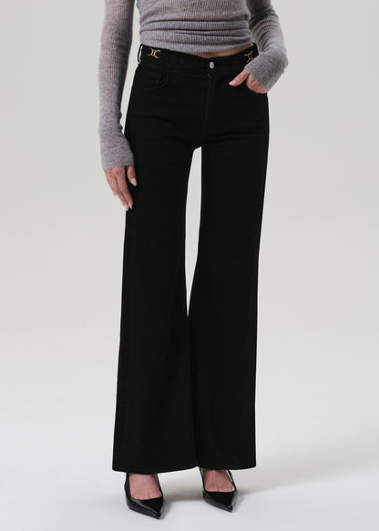 Person wearing black flared jeans and a gray sweater on a white background