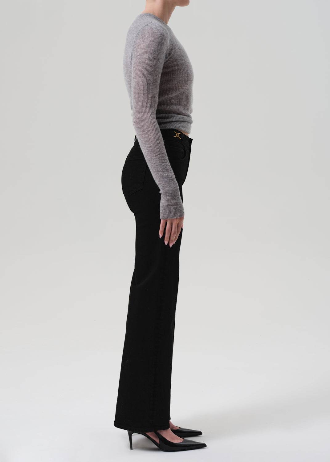 Person wearing a gray sweater and black pants on a white background