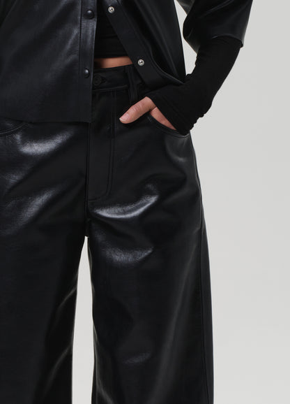 Person wearing black leather pants and jacket on a plain background