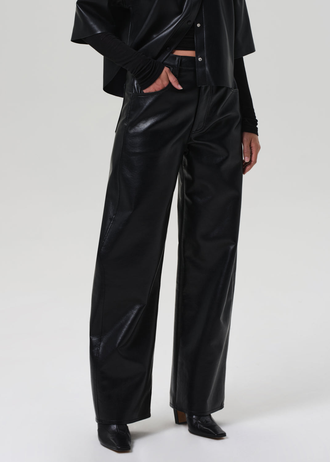Person wearing black vinyl pants on a grey background