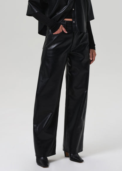 Person wearing black vinyl pants on a grey background