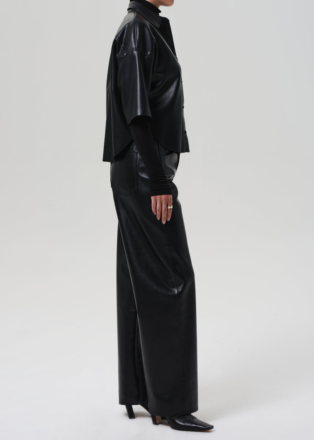 Person wearing a black leather outfit on a grey background