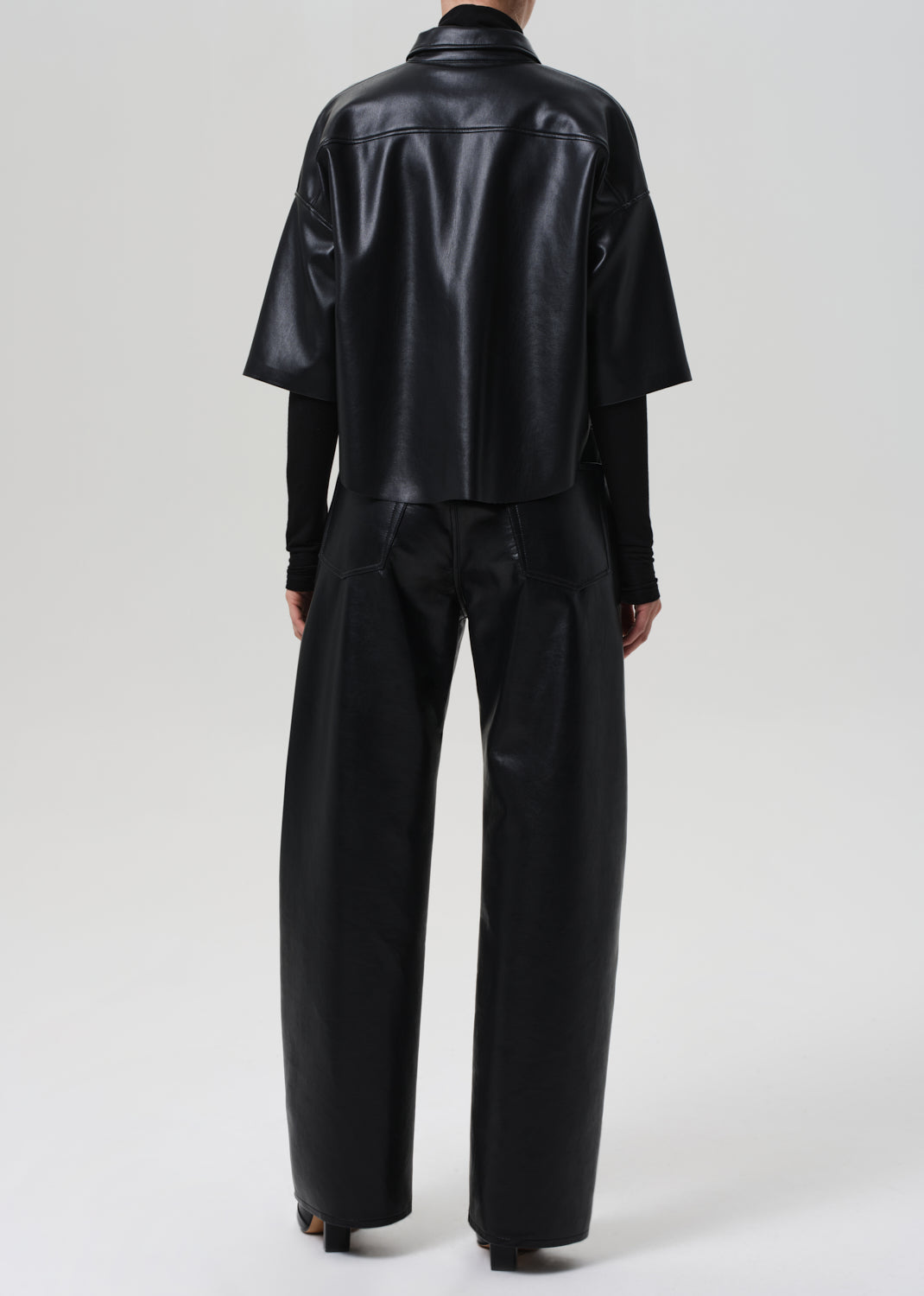 Person wearing a black leather outfit on a grey background