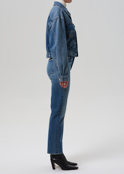 Person wearing a blue denim jacket and jeans on a grey background