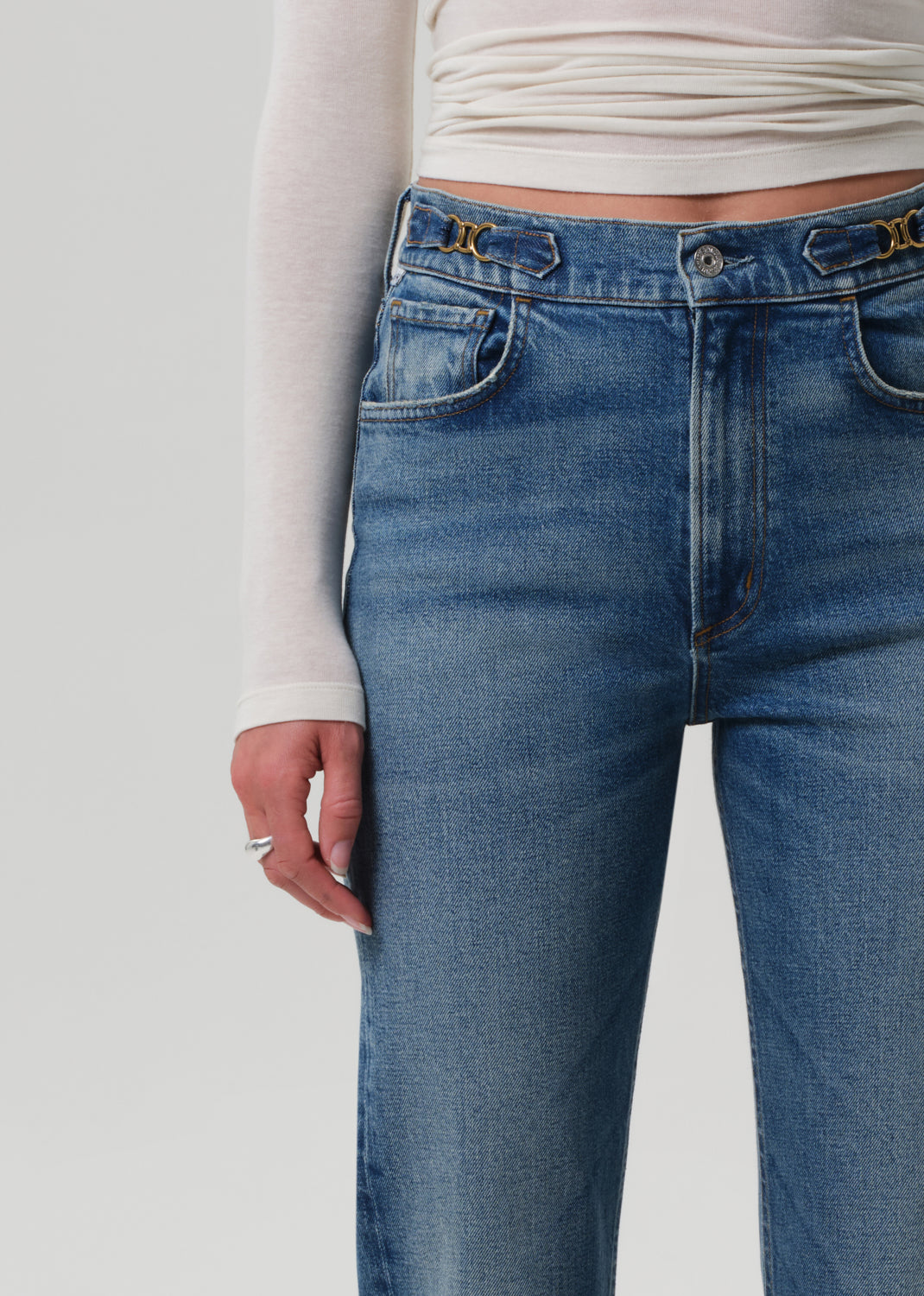 Person wearing a white shirt and jeans on a grey background