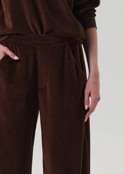 Person wearing a brown matching velour set on a grey background