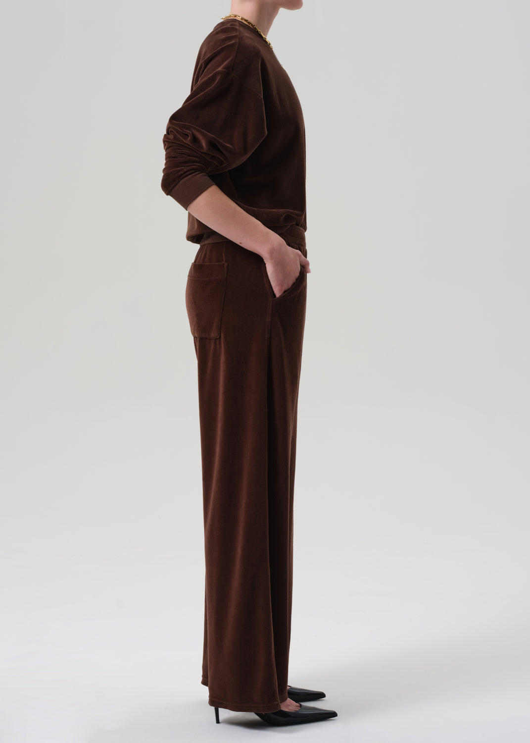 Person wearing a brown matching velour set on a grey background