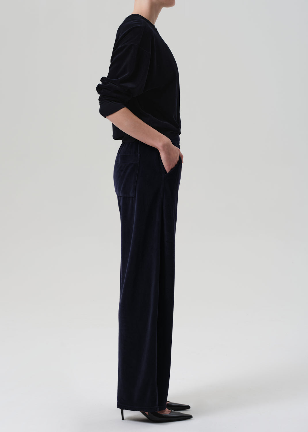 Person wearing a navy velvet set with wide-leg pants on a grey background