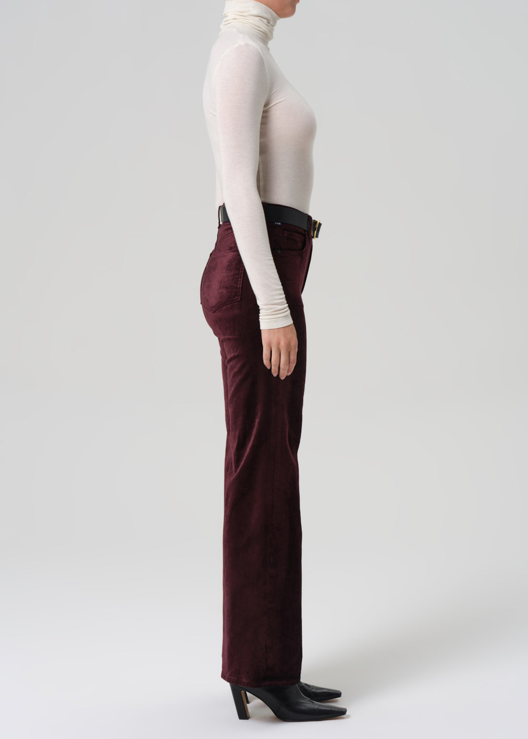 Person wearing burgundy pants and a white turtleneck on a white background