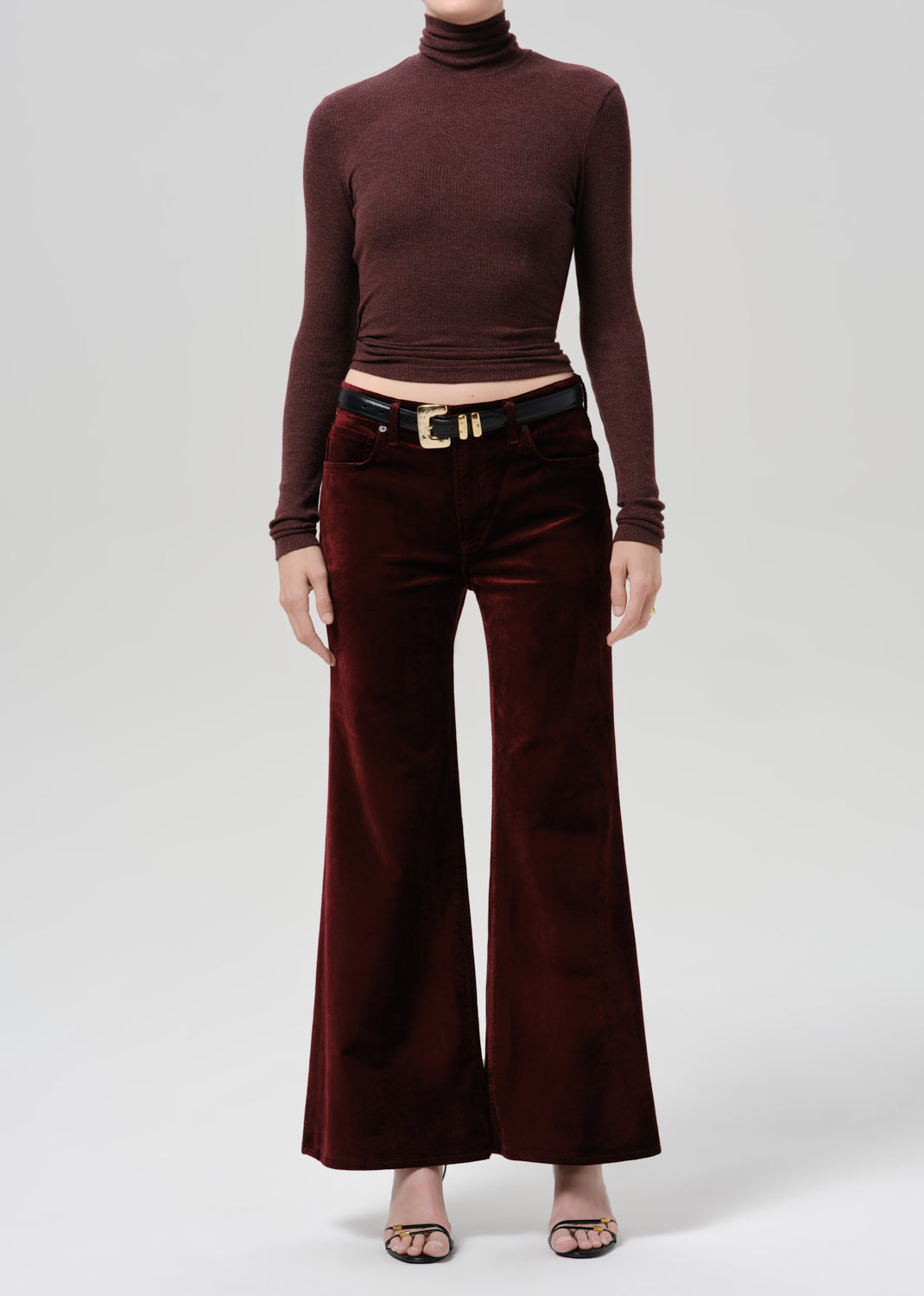 Person wearing a burgundy fitted turtleneck with burgundy wide leg pants on a grey background