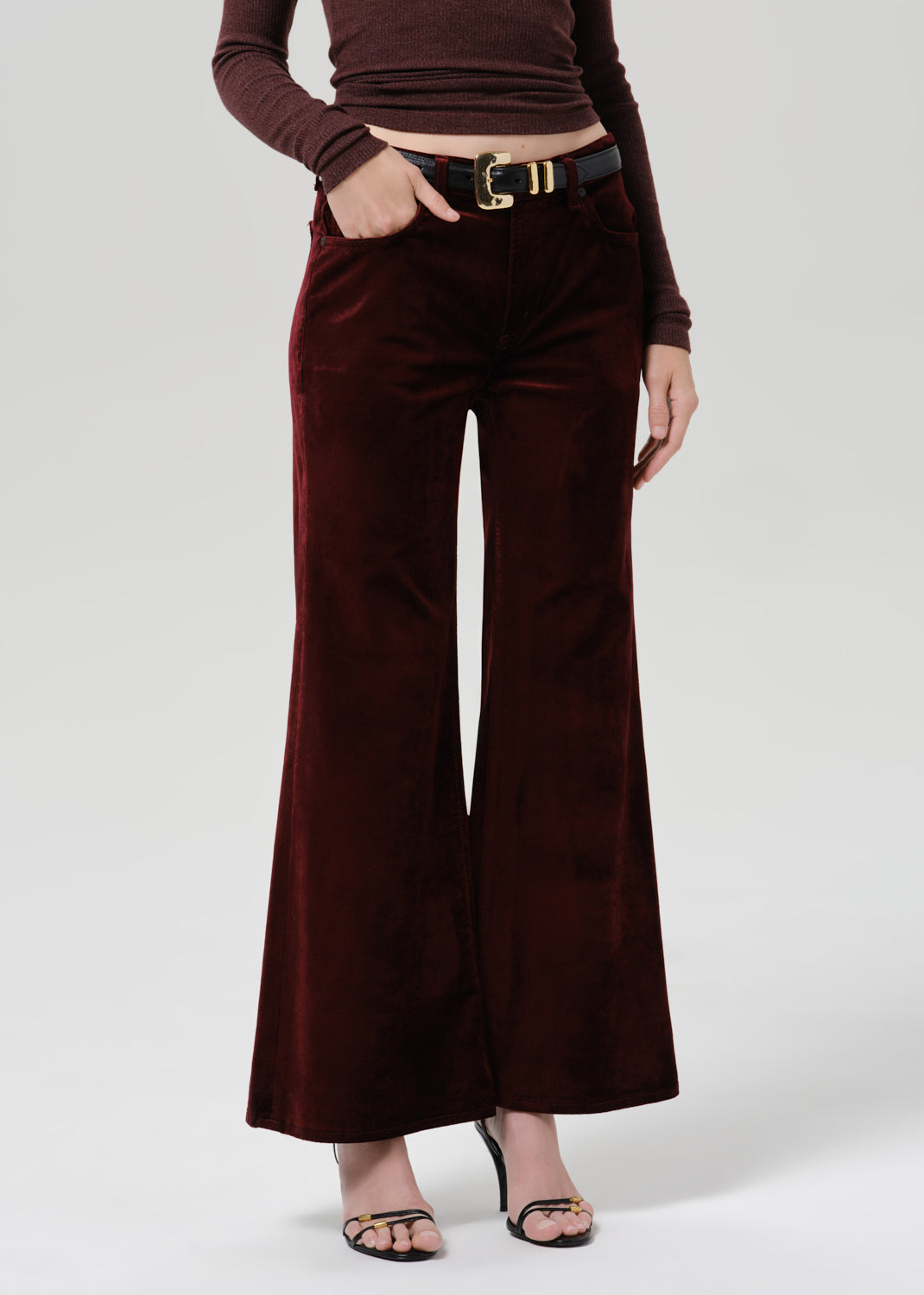 Person wearing a burgundy fitted turtleneck with burgundy wide leg pants on a grey background