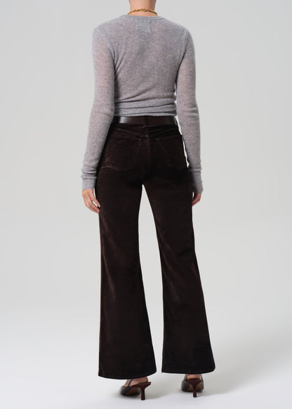 Person wearing a gray sweater and dark brown flared pants on a white background