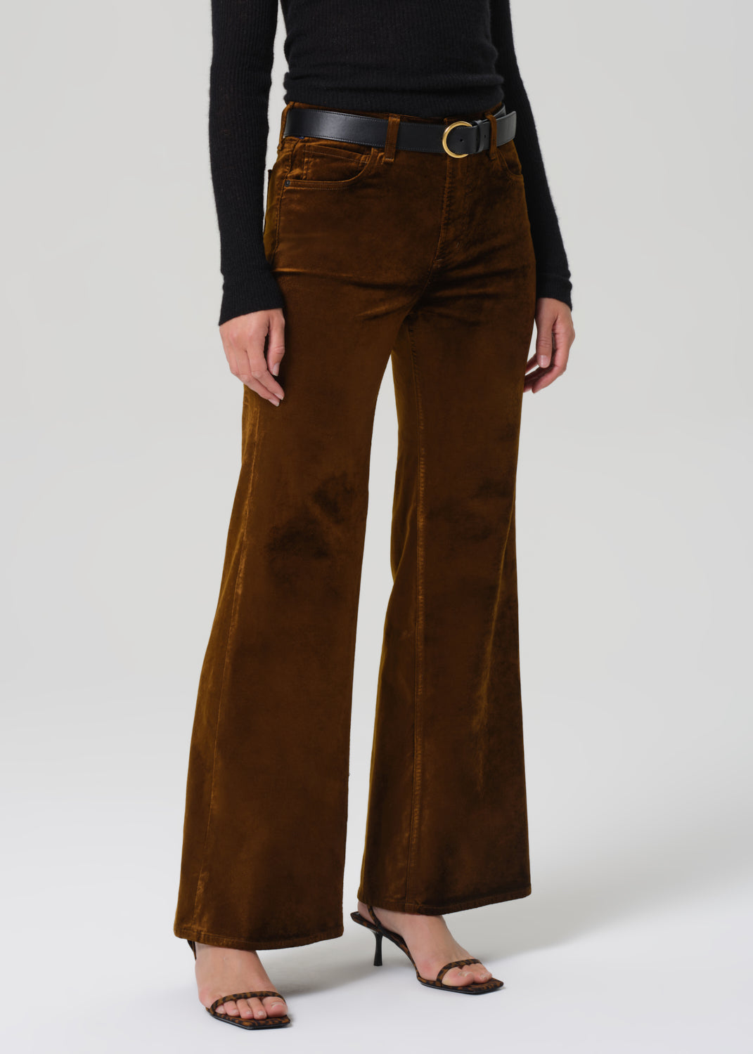 Brown corduroy pants worn by a person on a white background