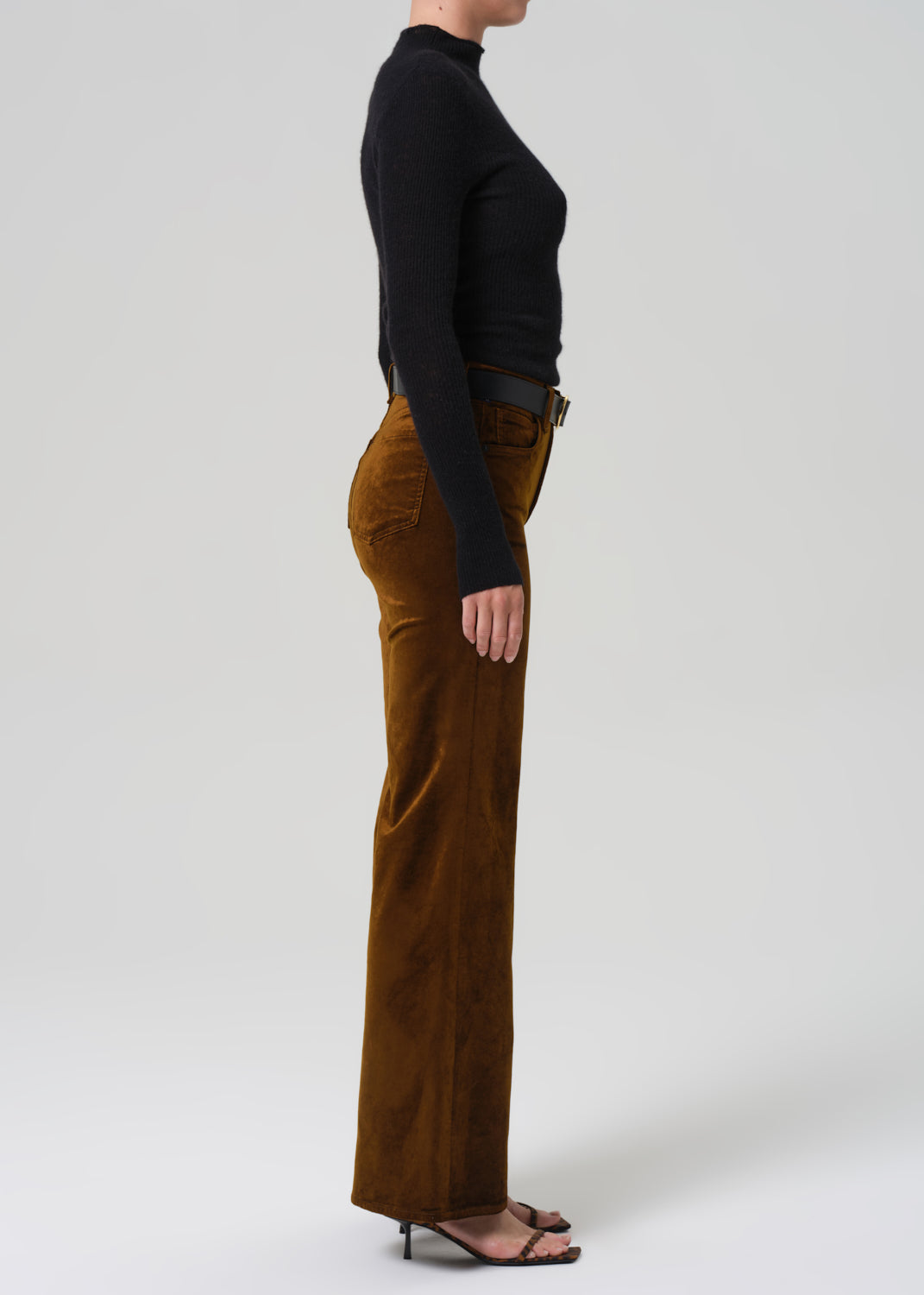 Person wearing brown corduroy pants and a black top on a white background