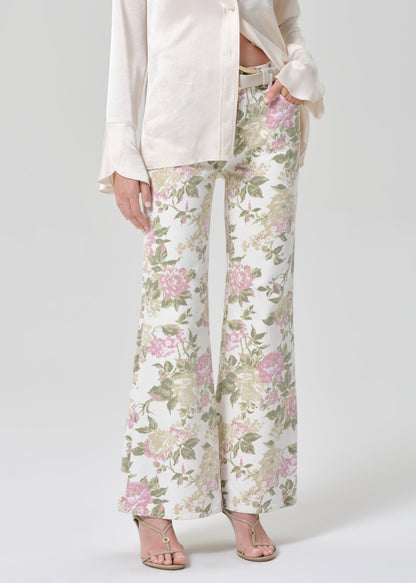 Person wearing a cream shirt and floral flare jeans on a grey background