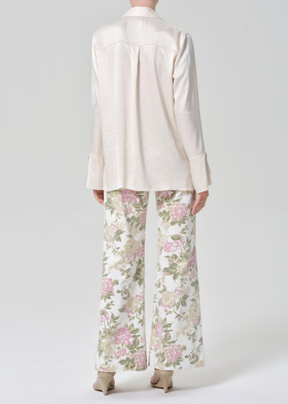 Person wearing a cream shirt and floral flare jeans on a grey background
