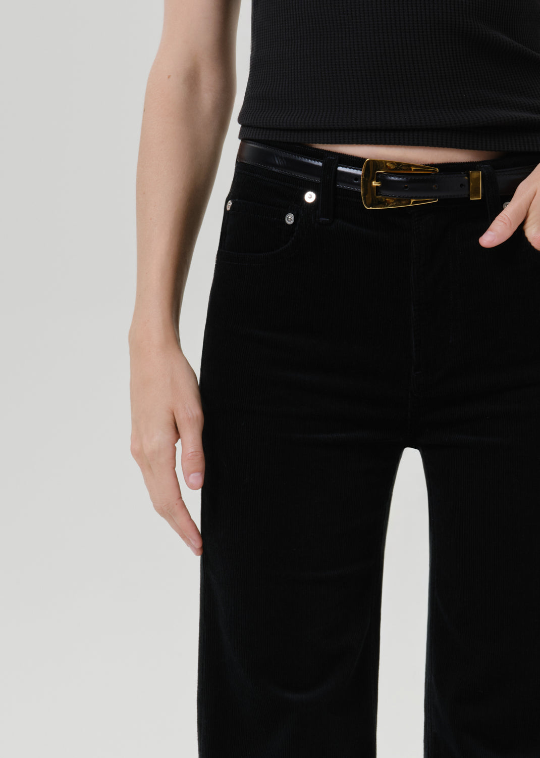 Close up of black pants with belt on a grey background