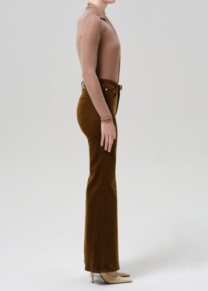 Person wearing tan bodysuit and orange flare corduroy pants on a grey background