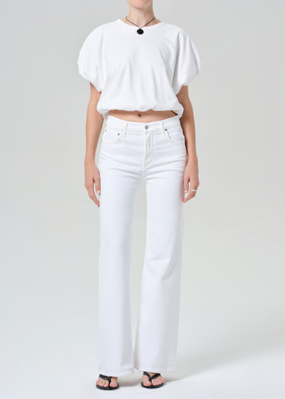 Person wearing a white shirt and white jeans on a plain background