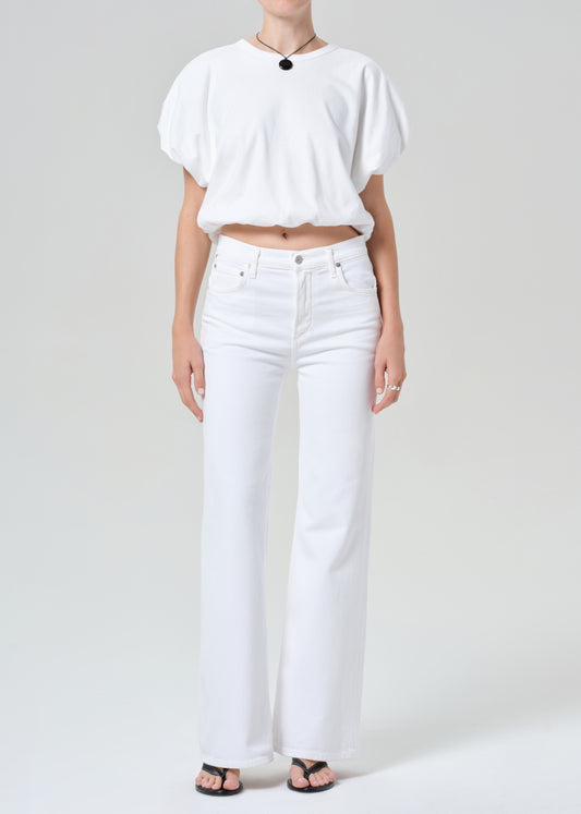 Person wearing a white shirt and white jeans on a plain background