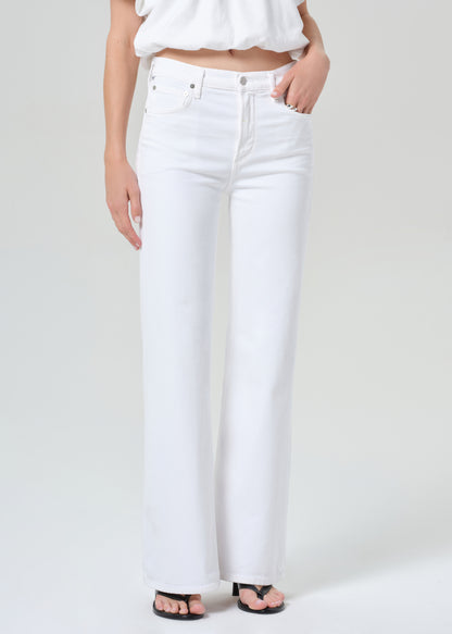 Person wearing a white shirt and white jeans on a plain background