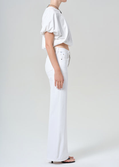 Person wearing a white shirt and white jeans on a plain background