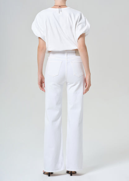 Person wearing a white shirt and white jeans on a plain background